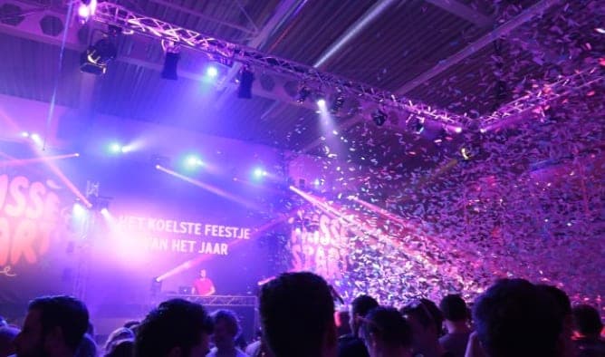 Feestzaal met confetti en de tekst "Het koelste feestje van het jaar"