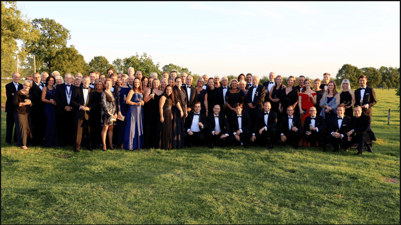 Groepsfoto van (oud-)Tafelaars en partners in het weiland tijdens het lustrumfeest